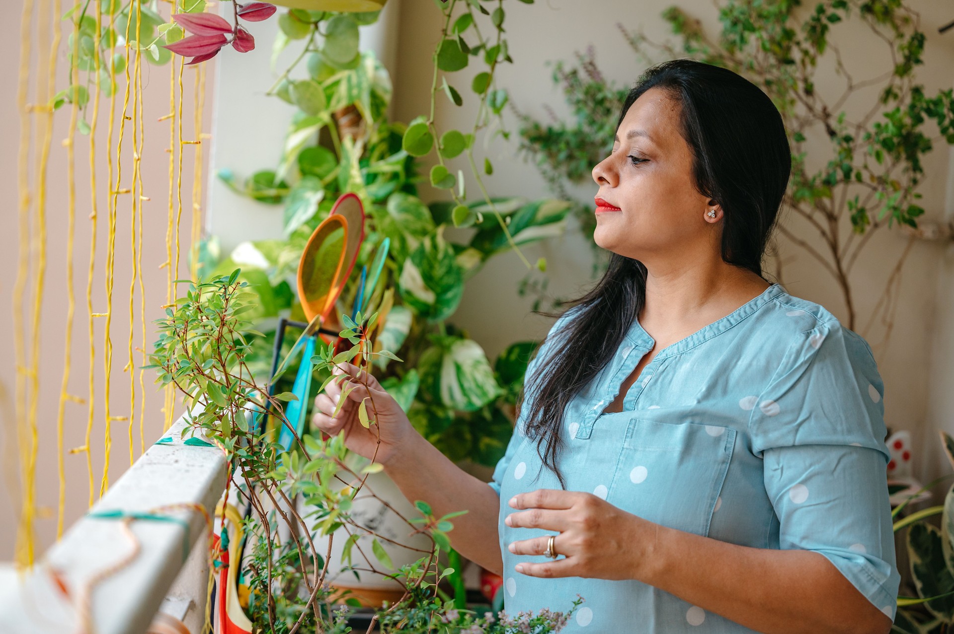 Woman decorating her balcony using green potted plants.